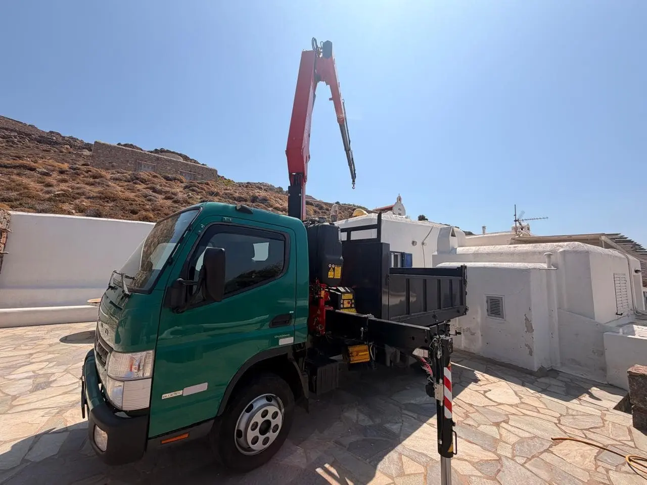 Crane truck lifting materials at a whitewashed Mykonos house